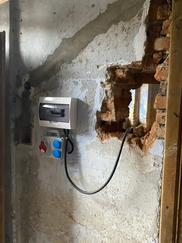 Staveništní rozvaděč a jističe uvnitř — konečně kam zapojit nářadí. Kabel vede skrz zeď.