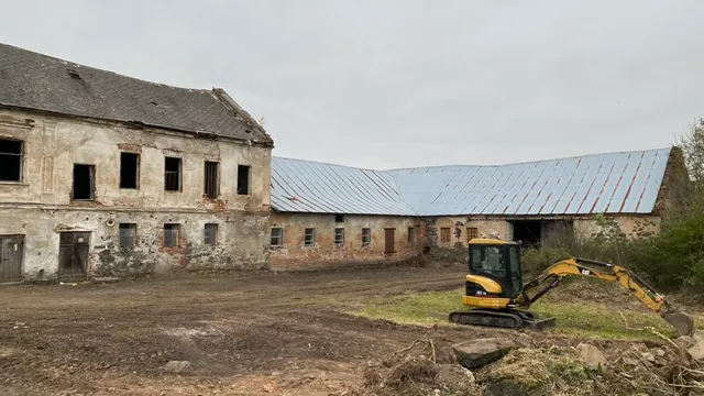 Srovnaný dvůr mezi zámečkem a stodolou. Bagr zvládl, co roky nešlo ručně.