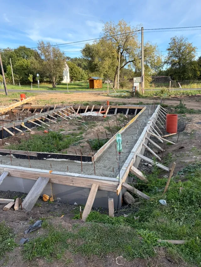 Čerstvý beton v pásu; bednění stále drží dřevěné vzpěry.