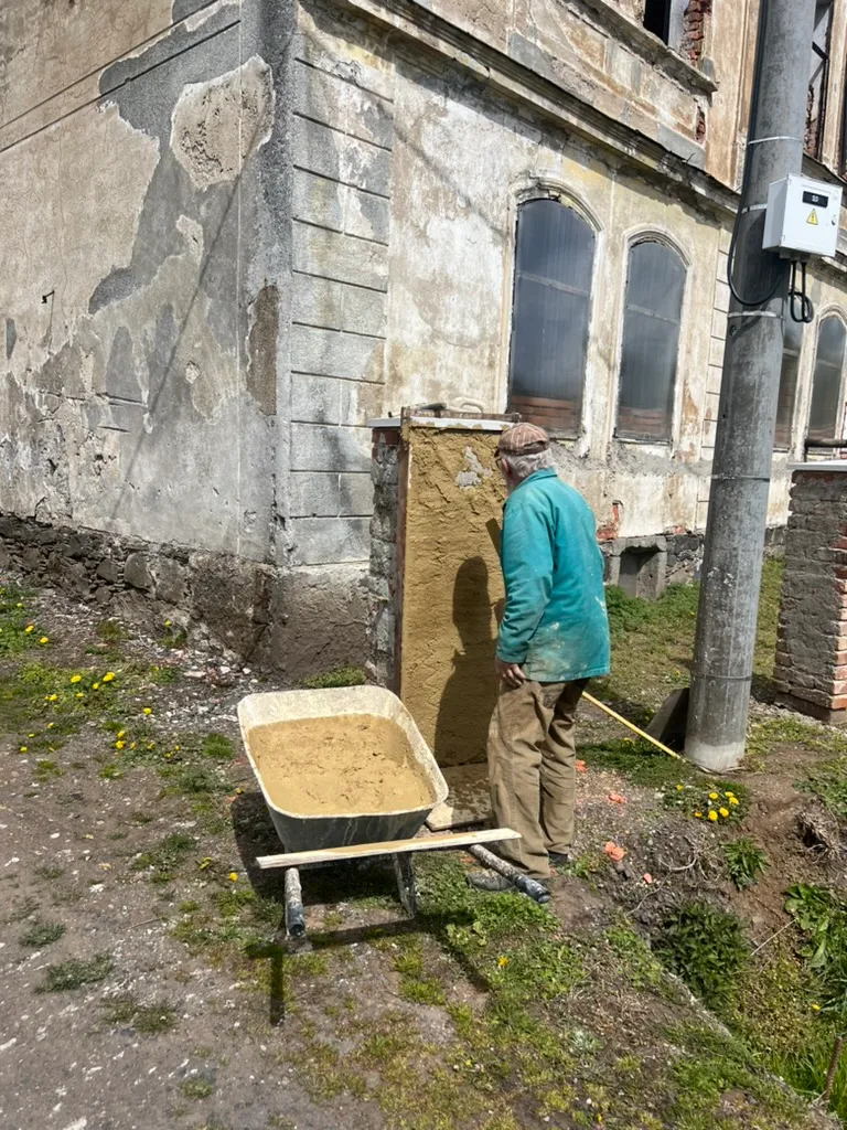 Děda omítá sloupek. Z holých cihel se stává čistý, hotově vypadající pilíř.