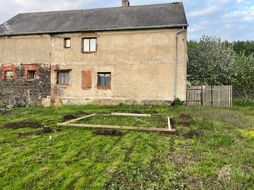 Kde bude pergola stát: podél boční stěny sousedního domu, čtyři metry od ní. Rámec z fošen vymezuje přesný půdorys.