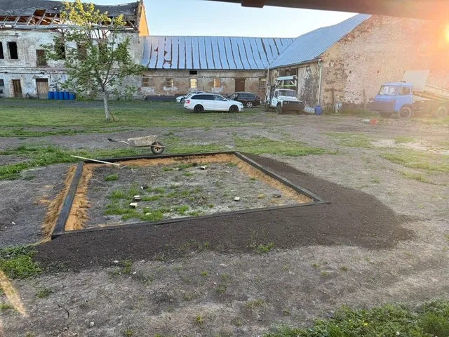 Rámec za soumraku, kolečko připravené na další den. V pozadí statek se stodolou.