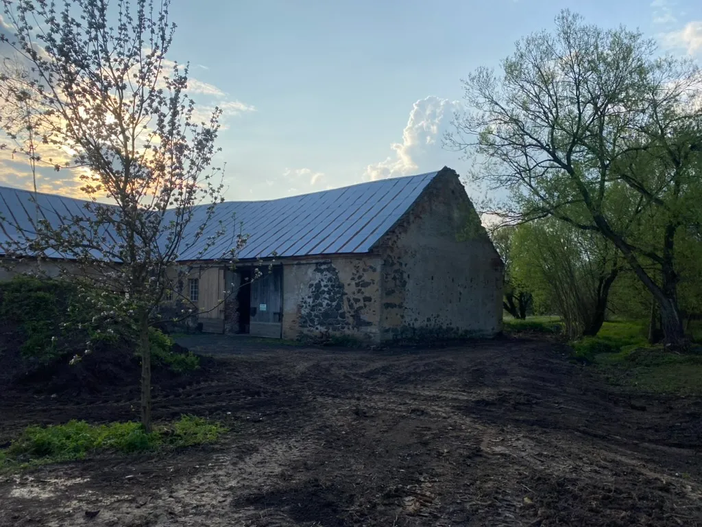 Stodola podvečer, terén před ní čerstvě srovnaný. Kvetoucí jabloň jako bonus.