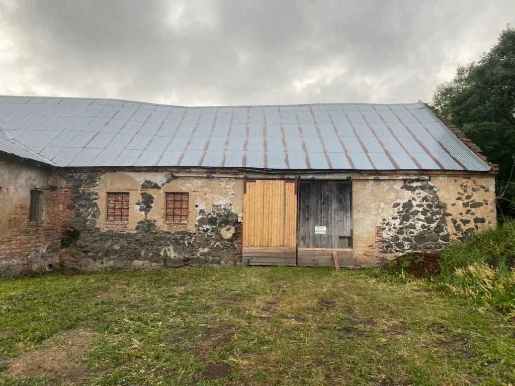 Stodola zvenku s novými dřevěnými vraty. Konečně se dá zamknout.