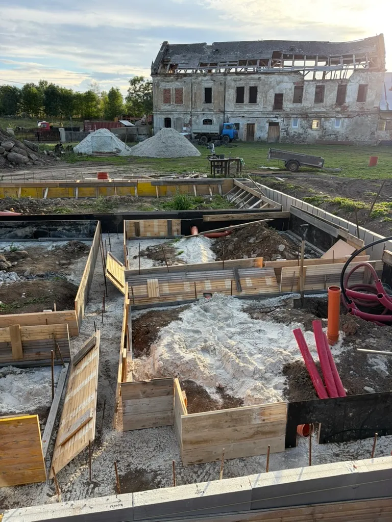 Dřevěné a černé bednicí desky postupně rozdělují prostor uvnitř základů.