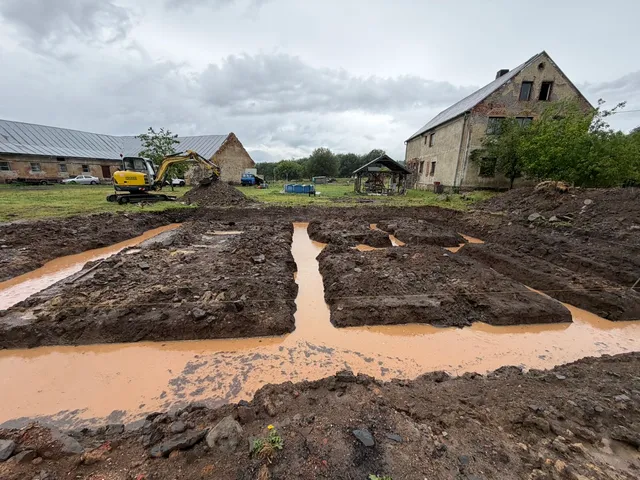 Pohled přes základové pásy: kalná voda se drží všude, kam výkop pustí.