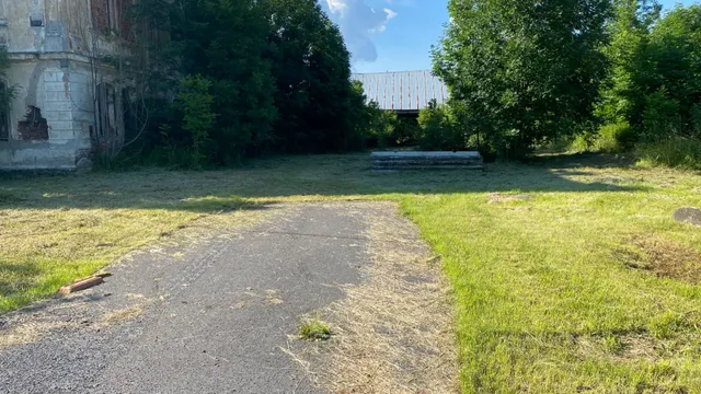 Asfalt končí pár metrů od silnice, dál už jen tráva. Fasáda pamatuje lepší časy.