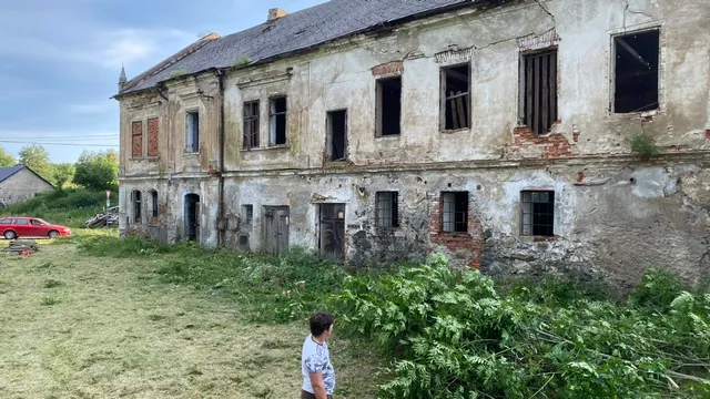 Fasáda ze dvora — prázdná okna, obnažené cihly, ale pořád stojí zpříma.