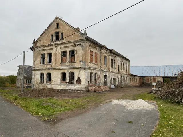 Zámeček od cesty — vlevo navezená zemina, vpravo připravený materiál.
