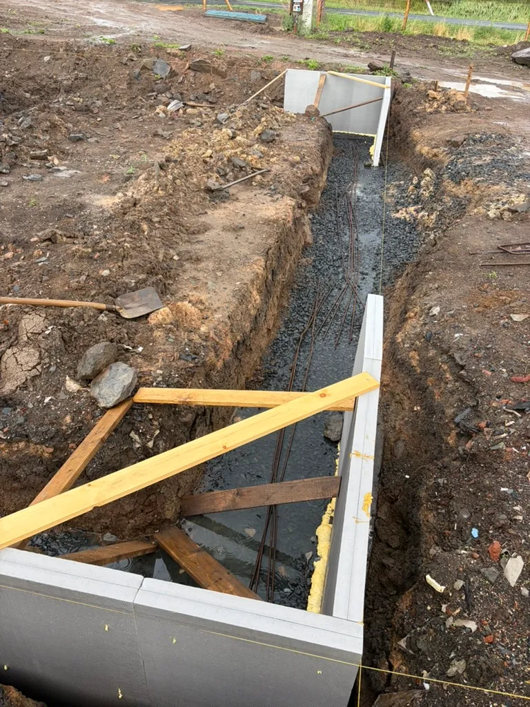 Detail provizorního zapření desek XPS prkny přes široký výkop. Právě tady je vidět, proč to nebyla jednoduchá skládačka.