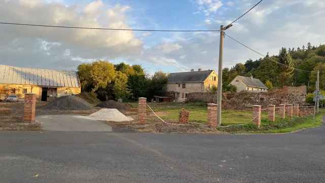 Na podzim už mají sloupky betonové čepice. Mezi nimi provizorně natažená páska, v pozadí podzimní statek.