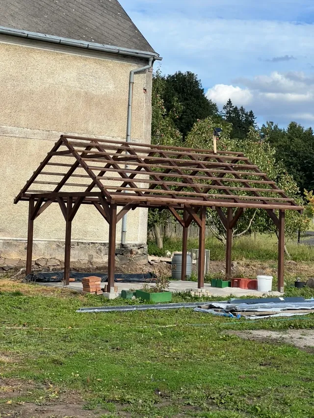4. září: zalaťovaný krov a krytina připravená na zemi. Pergole zbývá poslední krok — pokrýt střechu.